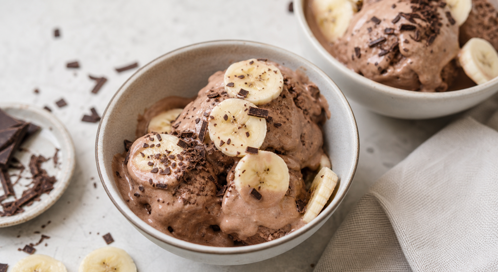 Cremige Schoko-Bananen-Nicecream in Schalen mit Bananenscheiben und Schokoraspeln